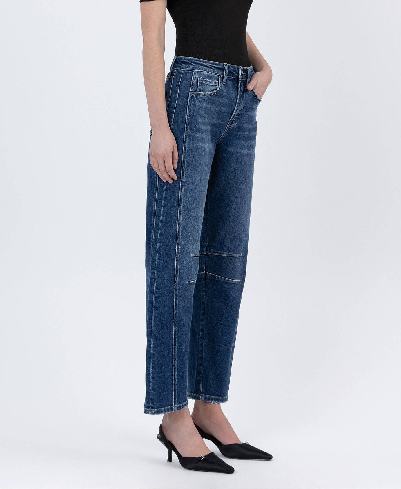 Woman wearing a black off-shoulder top and blue jeans on a white background