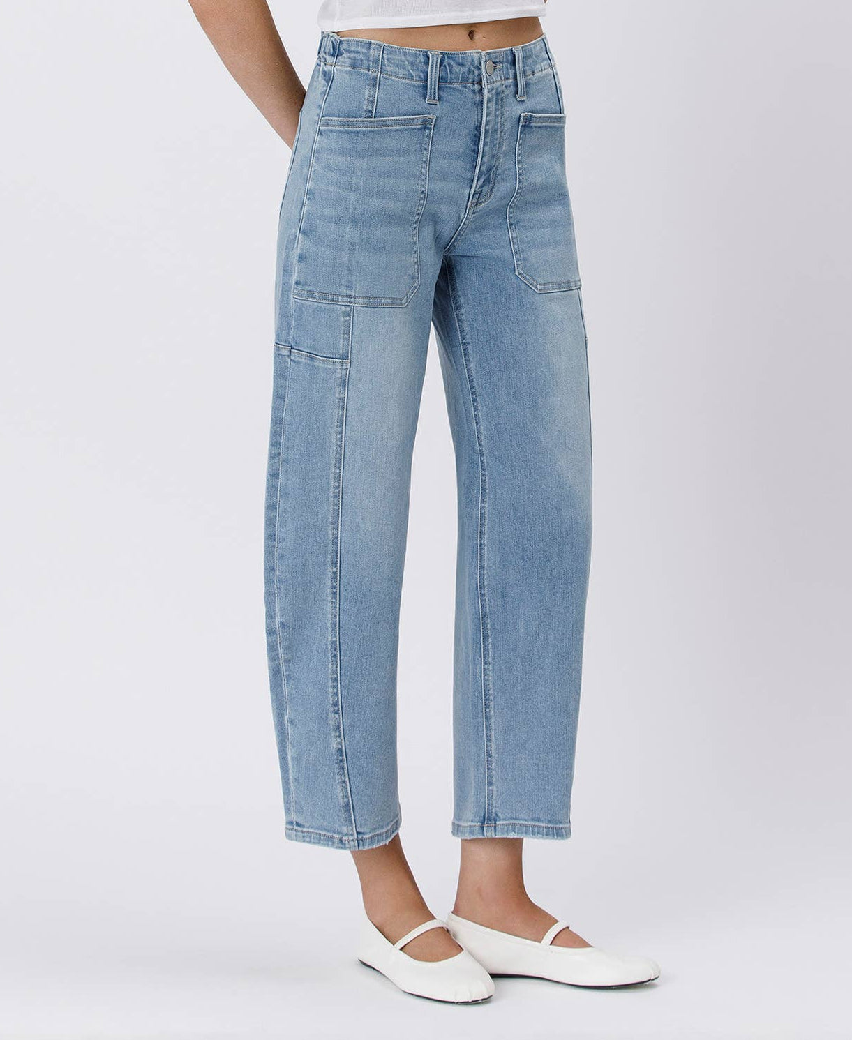 Woman wearing a white crop top and light blue jeans on a white background